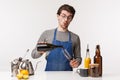 Barista, cafe worker and bartender concept. Portrait of silly handsome young man in apron pouring wine in glass and