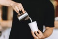 Barista carefully pours the milk into a glass in a modern coffee shop.