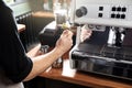 Barista cleaning coffee machine steam wand with rag on bar counter