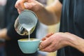 Barista in coffee bar preparing proper cappuccino pouring frothed milk into cup of coffee, making latte art, pattern