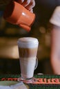 Barista creating latte art on long coffee with milk. Latte art in coffee mug. Barman pouring fresh coffee. Royalty Free Stock Photo