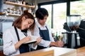 Barista girl or coffee maker answer mobile phone also record the order detail into notebook while her co-worker is working with