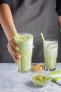 Barista girl serves a glass of matcha green tea. Cropped photo. Useful latte