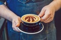 Barista hands holding black cup of coffee cappuccino with Toronto Raptors basketball team logo sign on milk foam