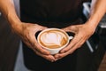 Barista hands holding a cup of hot heart-shaped latte art. Latte coffee with swirl milk decoration Royalty Free Stock Photo