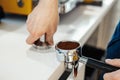 Barista hands holding portafilter and coffee tamper making an espresso coffee.