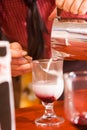 Barista hands pour milk foam into freshly cooked coffee from coffee pot in transparent glass cup, photo