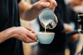 Barista hands pouring warm milk in coffee cup for making latte art. Professional coffee making, service Royalty Free Stock Photo