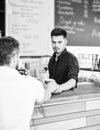 Barista handsome stylish hipster communicate with client visitor. Served coffee to go. Man ask for drink at bar counter Royalty Free Stock Photo