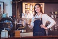 Barista holding coffee cup and smiles in her cafe