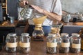 Barista holding drip pot and pouring water onto ground coffee beans in the paper filter for brewing drip coffee at the cafe in the Royalty Free Stock Photo