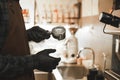 Barista holding portafilter making espresso coffee at the cafe at the coffee machine. Male bartender in the black gloves making Royalty Free Stock Photo