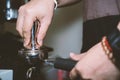 Barista holding tamper in one hand going to press ground coffee in holder to make espresso Royalty Free Stock Photo