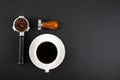 Barista Kit. Coffee Tamper Brown Wooden Handle, coffee horn with beans and white cup espresso, flatlay on black background. Barman