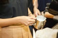 Barista make a cappuccino or latte steaming and frothing milk