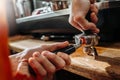 Barista making coffee and holding a portafilter in hands and pressing coffee. Close-up.