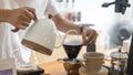 Barista is making drip brewing, filtered coffee, or pour over coffee with hot water and filter paper in coffee shop and drip