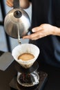 Barista making drip coffee by pouring hot water from goose neck kettle to filter cone Royalty Free Stock Photo