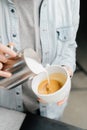 Barista making latte art in specialty coffee shop. Professional man making pouring stream milk with espresso