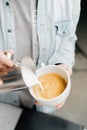 Barista making latte art in specialty coffee shop. Professional man making pouring stream milk with espresso