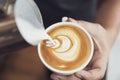 Barista making latte or Cappuccino art with frothy foam, coffee cup in cafe