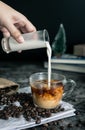 Barista making latte. hand pouring milk into a cup of espresso coffee, preparing coffee drink. vertical image, cropped shot. Royalty Free Stock Photo