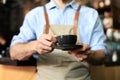 Barista offering a cup of coffee to camera at the coffee shop Royalty Free Stock Photo