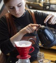 Barista pouring boiling water of manual drip brewer and make coffee. Girl pouring on coffee ground with filter. Alternative pure Royalty Free Stock Photo