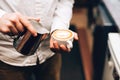 Barista pouring cappuccino into cup, making a delicious morning drink