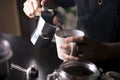 Barista pouring coffee from moka pot coffee maker to a coffee cup. Hand holding Italian classic moka pot pouring coffee Royalty Free Stock Photo