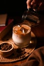 A barista pouring a cold brew coffee or dark coffee shot into a glass of iced with fresh milk Royalty Free Stock Photo