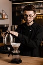 Barista pouring hot water over filter with ground coffee in the funnel. Drip filter coffee brewing. Pour over Royalty Free Stock Photo