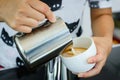 Barista pouring milk in capuccino coffee