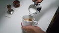 Barista pouring milk coffee from pitcher close up. Process preparing cappuccino.