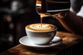 Barista pouring milk into a cup of hot latte art coffee, Barista pouring milk into a cup of latte art coffee. A coffee cup in a Royalty Free Stock Photo