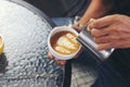 Barista pouring milk foam for making coffee latte art with pattern the leaves in a cup Royalty Free Stock Photo