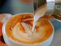 barista pouring milk latte art from silver pitcher into the hot coffee cup. Royalty Free Stock Photo