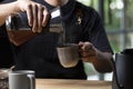 Barista pouring steaming drip coffee with smoke in to a cup on a work desk in coffee shop