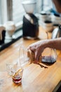 Barista pours coffee brewed according to an alternative method from a transparent jug into glass cup on a table in a coffee shop