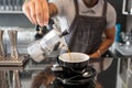 Barista pours coffee from the coffee pot inside contemporary design style cafe with bar Royalty Free Stock Photo