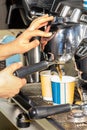 A barista prepares coffee in a coffee machine and pours it into paper cups Royalty Free Stock Photo