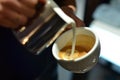 Barista prepares coffee latte.