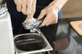 Barista preparing Coffee by holding portafilter and coffee tamper making an espresso coffee