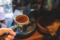Barista presses ground coffee using tamper