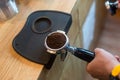 Barista pressing coffee in the machine holder. Coffee powder on coffee tamper. barista using tamper to press ground coffee into po