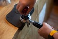 Barista pressing coffee in the machine holder. Coffee powder on coffee tamper. barista using tamper to press ground coffee into po