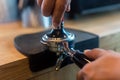 Barista pressing coffee in the machine holder. Coffee powder on coffee tamper. barista using tamper to press ground coffee into po Royalty Free Stock Photo