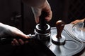 Barista pressing ground coffee into portafilter with a tamper