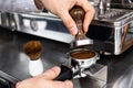 Barista pressing ground coffee into portafilter with a tamper.