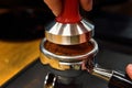 Barista puns ground coffee by using the tamper. Preparing coffee for coffee machine Royalty Free Stock Photo